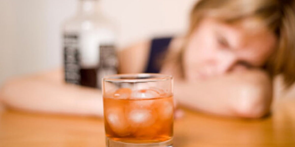 Una mujer ante un vaso con alcohol