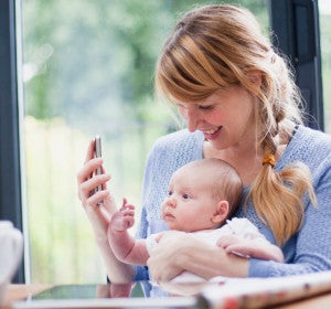 Una madre con su bebé mirando un smartphone Una madre con su bebé mirando un smartphone