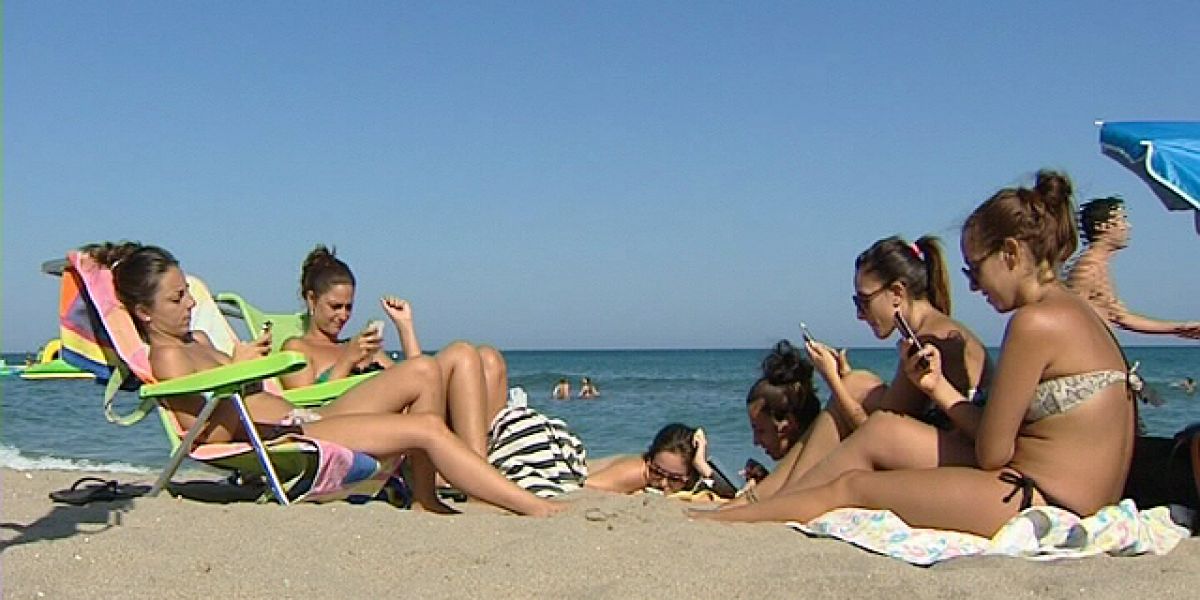 Un grupo de chicas con sus móviles en la playa