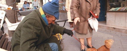 Un mendigo descansa en un banco en una c