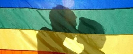 Dos jóvenes se besan tras la bandera LGTB Dos jóvenes se besan tras la bandera LGTB