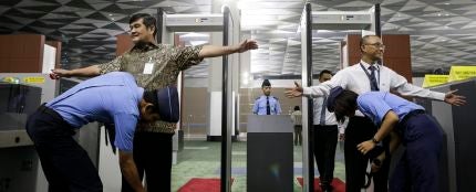 Oficiales de seguridad inspeccionan a los pasajeros en un punto de control de un aeropuerto