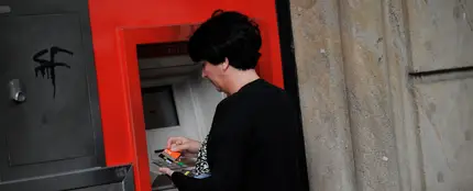 Una mujer saca dinero de un cajero automático Una mujer saca dinero de un cajero automático