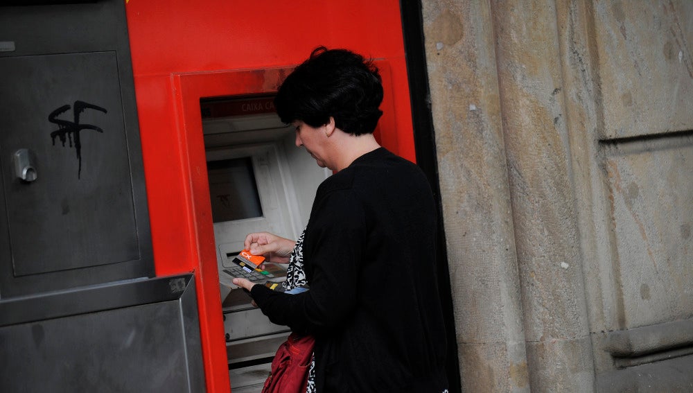 Una mujer saca dinero de un cajero automático