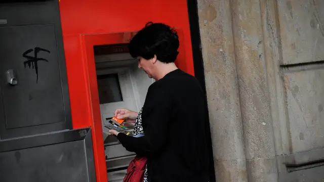 Una mujer saca dinero de un cajero automático
