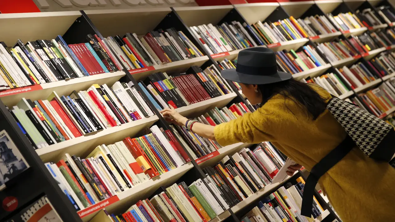 Una mujer mira libros en los estanterías de una librería Una mujer mira libros en los estanterías de una librería