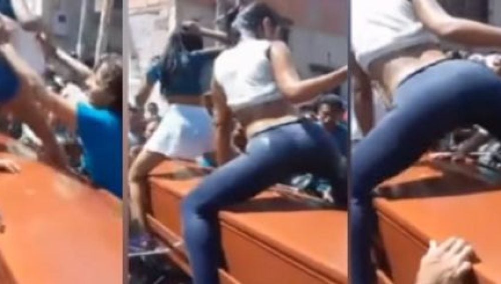 Dos chicas bailando reggaeton sobre un ataúd
