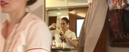 La azafata rellenando una botella de champagne con las sobras de la copas La azafata rellenando una botella de champagne con las sobras de la copas