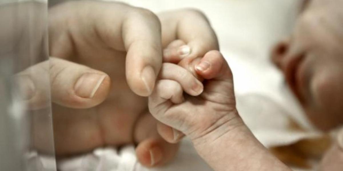 Un bebe coge de la mano a su madre