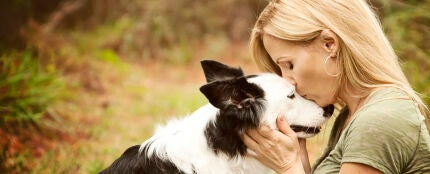 Una mujer d&aacute;ndole un beso a su perro