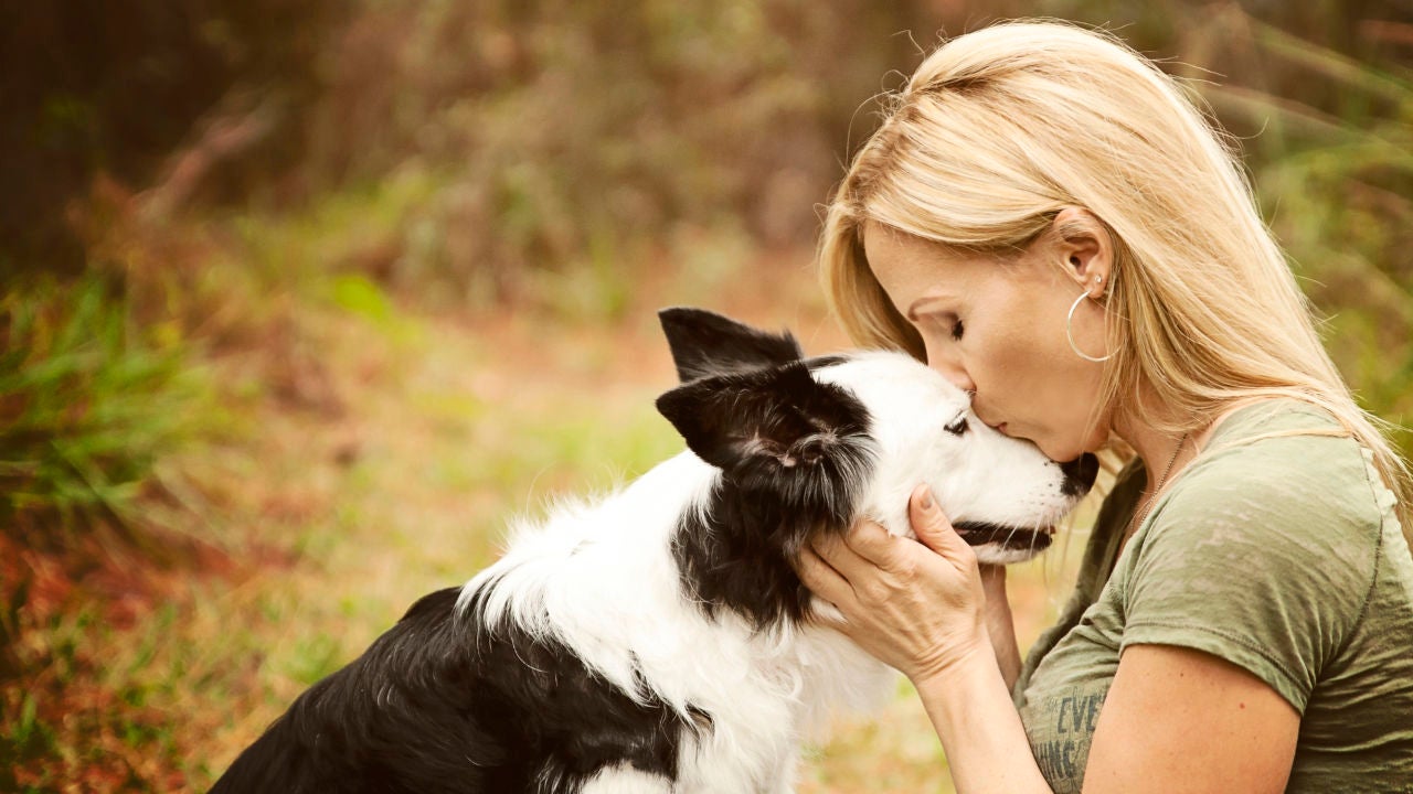 Una mujer dándole un beso a su perro Una mujer dándole un beso a su perro