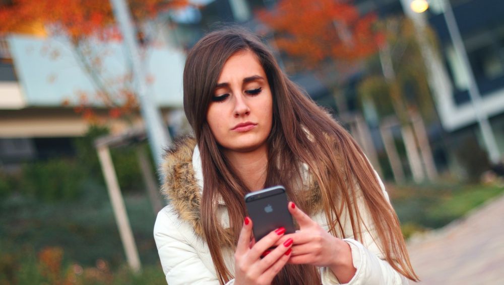 Una adolescente mira el móvil