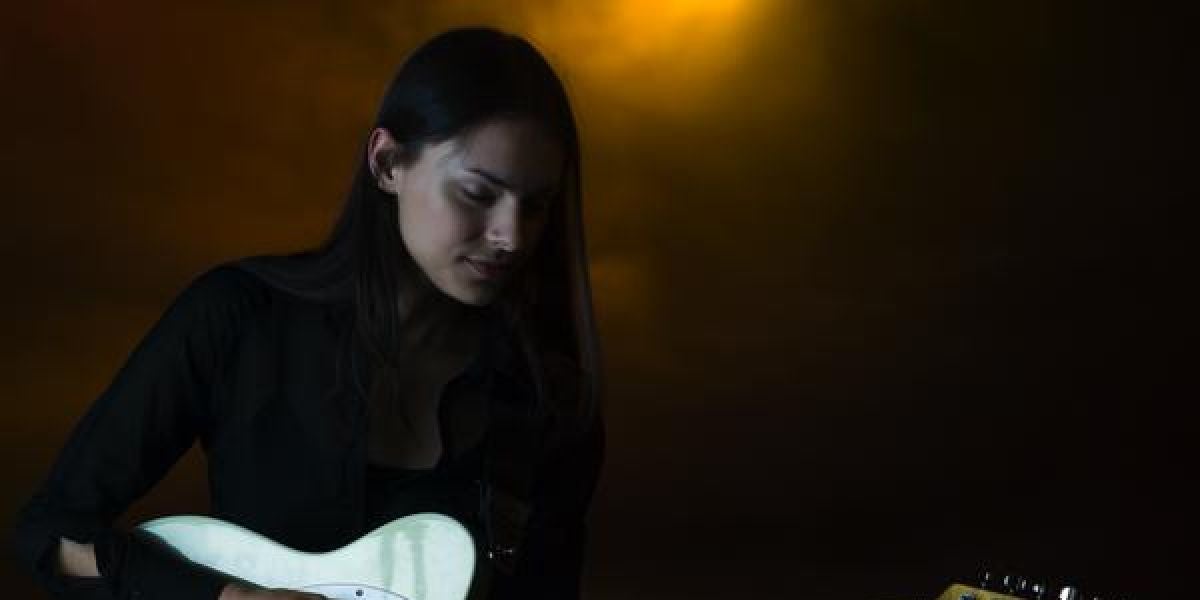 Una chica tocando la guitarra eléctrica en un pub