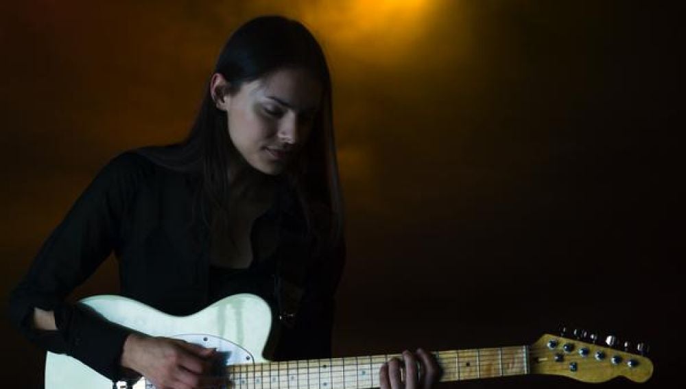 Una chica tocando la guitarra eléctrica en un pub