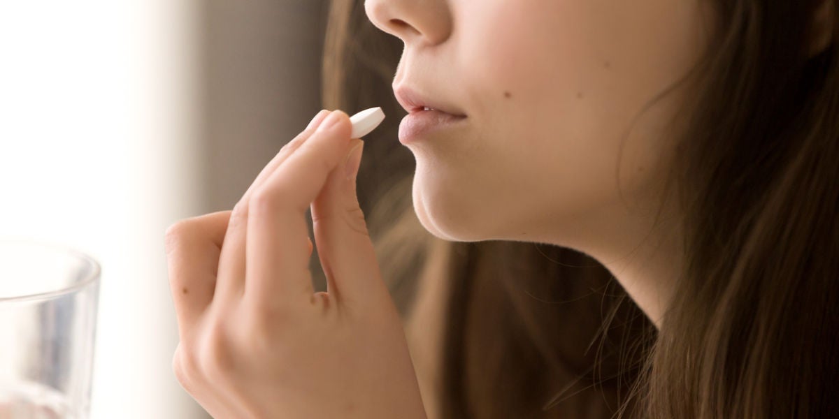 Imagen de una mujer tomando una pastilla.
