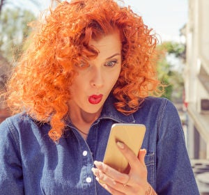 Mujer sorprendida al mirar el móvil Mujer sorprendida al mirar el móvil