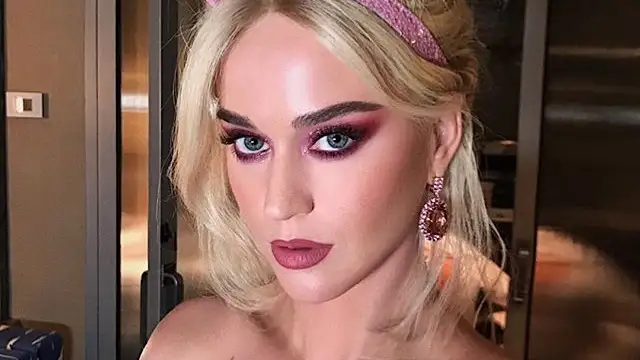 Katy Perry con la melena rubia y un mono de color rosa pastel