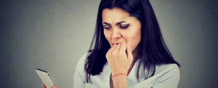 Mujer inquieta al revisar el m&oacute;vil