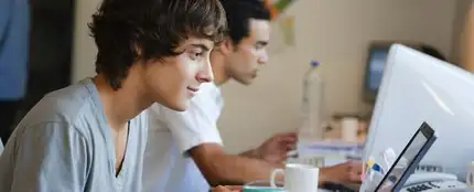Chico mirando el portátil en una cafetería Chico mirando el portátil en una cafetería