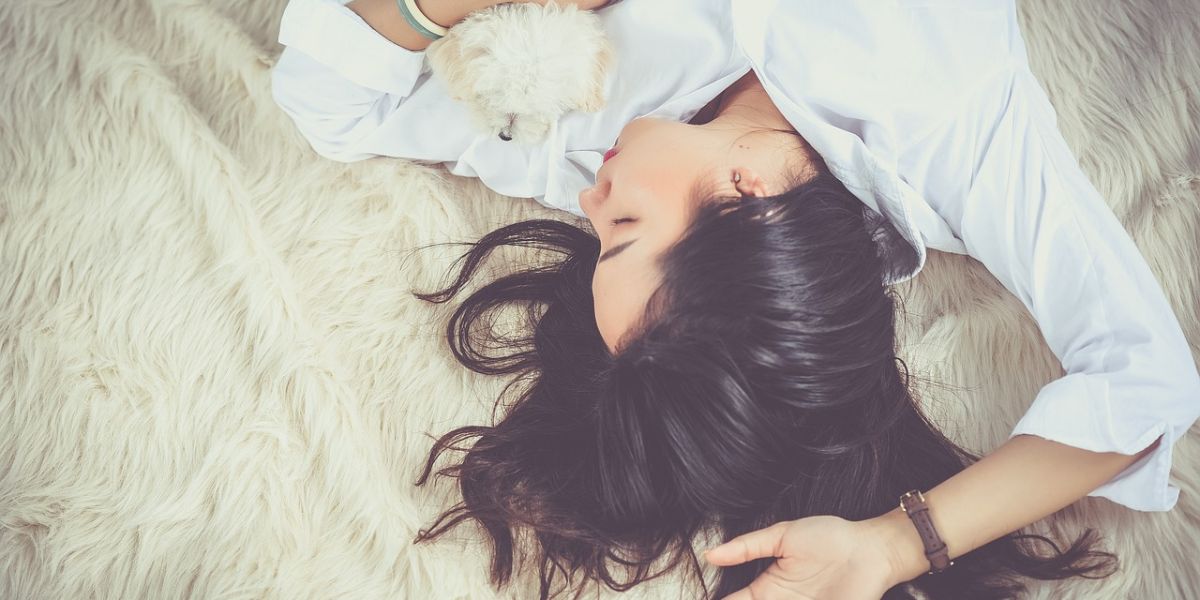 mujer durmiendo en una cama con un perro