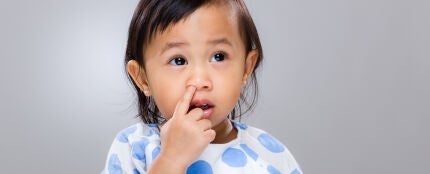 Una niña pequeña metiéndose el dedo en la nariz