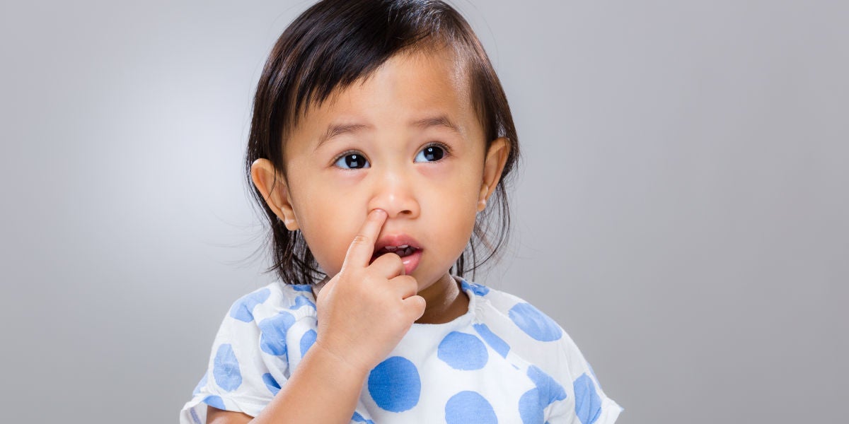 Una niña pequeña metiéndose el dedo en la nariz