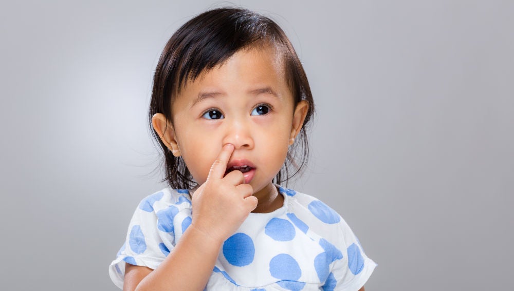 Una niña pequeña metiéndose el dedo en la nariz
