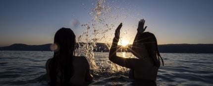Dos adolescentes disfrutan de la puesta de sol en el agua del Lago de Neuchatel