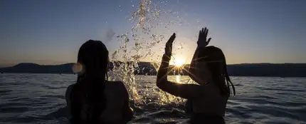 Dos adolescentes disfrutan de la puesta de sol en el agua del Lago de Neuchatel Dos adolescentes disfrutan de la puesta de sol en el agua del Lago de Neuchatel
