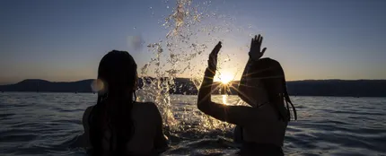 Dos adolescentes disfrutan de la puesta de sol en el agua del Lago de Neuchatel Dos adolescentes disfrutan de la puesta de sol en el agua del Lago de Neuchatel