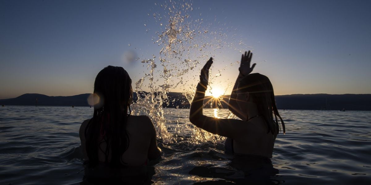Dos adolescentes disfrutan de la puesta de sol en el agua del Lago de Neuchatel