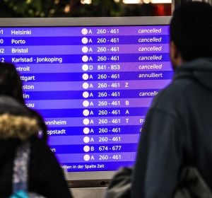 Unos pasajeros mirando los vuelos cancelados en la pantalla informativa Unos pasajeros mirando los vuelos cancelados en la pantalla informativa