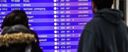 Unos pasajeros mirando los vuelos cancelados en la pantalla informativa