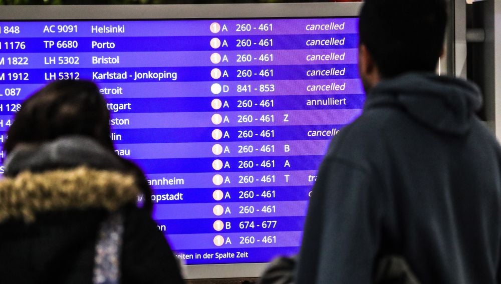 Unos pasajeros mirando los vuelos cancelados en la pantalla informativa