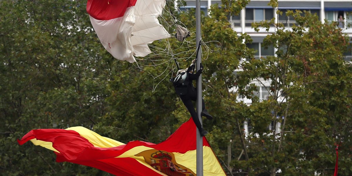 El paracaidista que descendía portando la bandera, en la farola en la que se enganchó