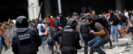 Miembros de los Mossos d'Esquadra cargan contra los centenares de personas que se agolpan ante el Aeropuerto del Prat Miembros de los Mossos d'Esquadra cargan contra los centenares de personas que se agolpan ante el Aeropuerto del Prat