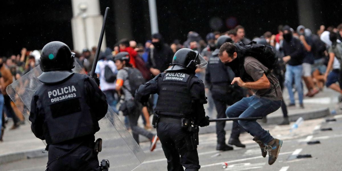 Miembros de los Mossos d'Esquadra cargan contra los centenares de personas que se agolpan ante el Aeropuerto del Prat