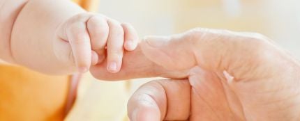 Una mano de adulto cogiendo la de un bebé