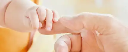 Una mano de adulto cogiendo la de un bebé Una mano de adulto cogiendo la de un bebé