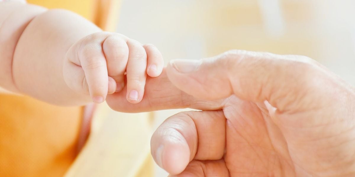 Una mano de adulto cogiendo la de un bebé