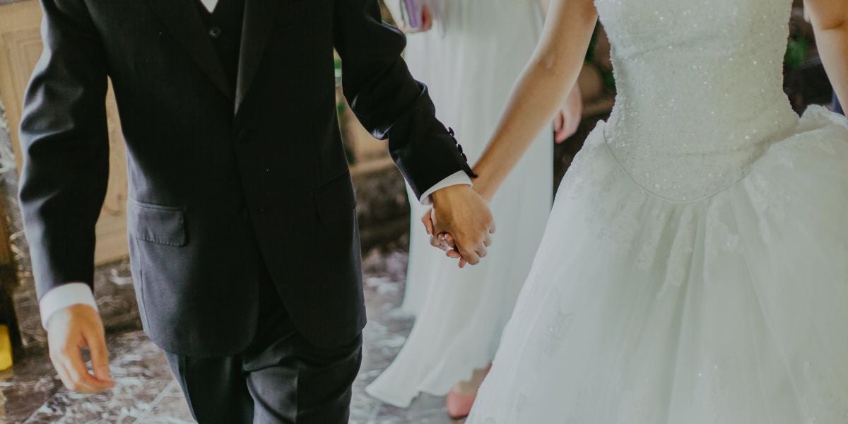 Unos novios cogidos de la mano en su boda
