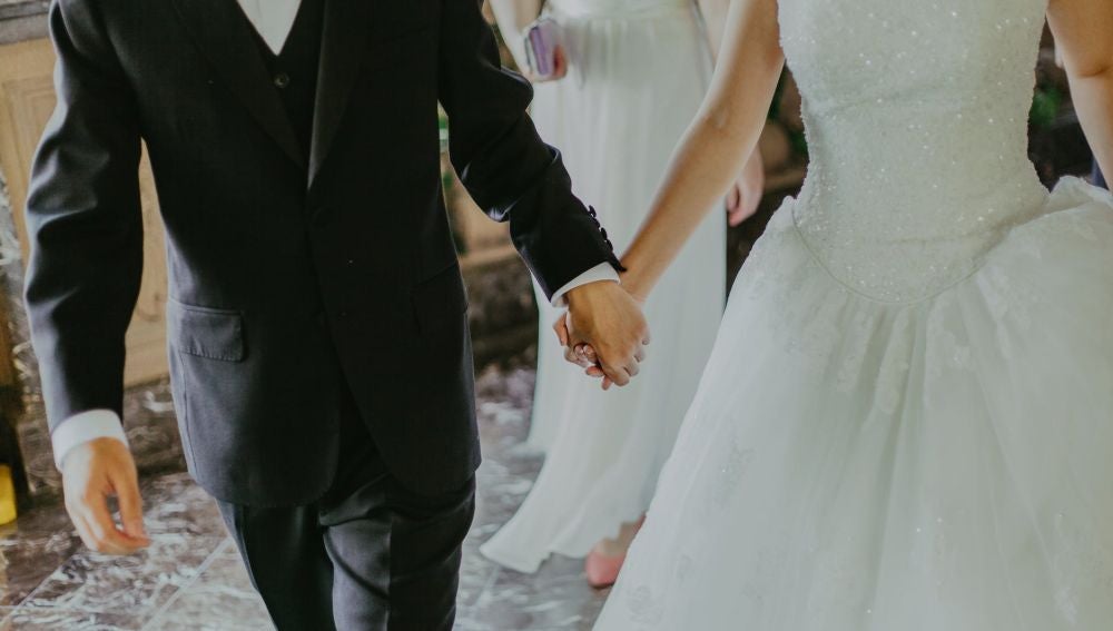 Unos novios cogidos de la mano en su boda