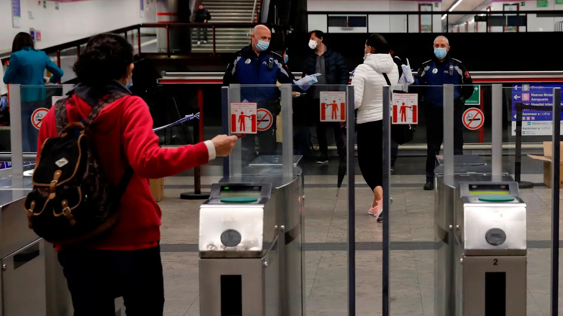 Policías entregan mascarillas en la estación de metro de Nuevos Ministerios en Madrid title=