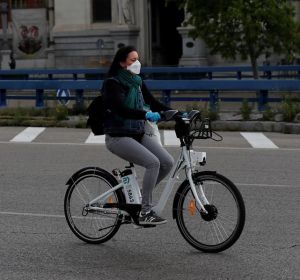 Una mujer con mascarilla y guantes usa una bici de biciMad en Madrid Una mujer con mascarilla y guantes usa una bici de biciMad en Madrid