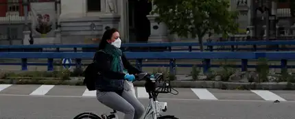 Una mujer con mascarilla y guantes usa una bici de biciMad en Madrid Una mujer con mascarilla y guantes usa una bici de biciMad en Madrid