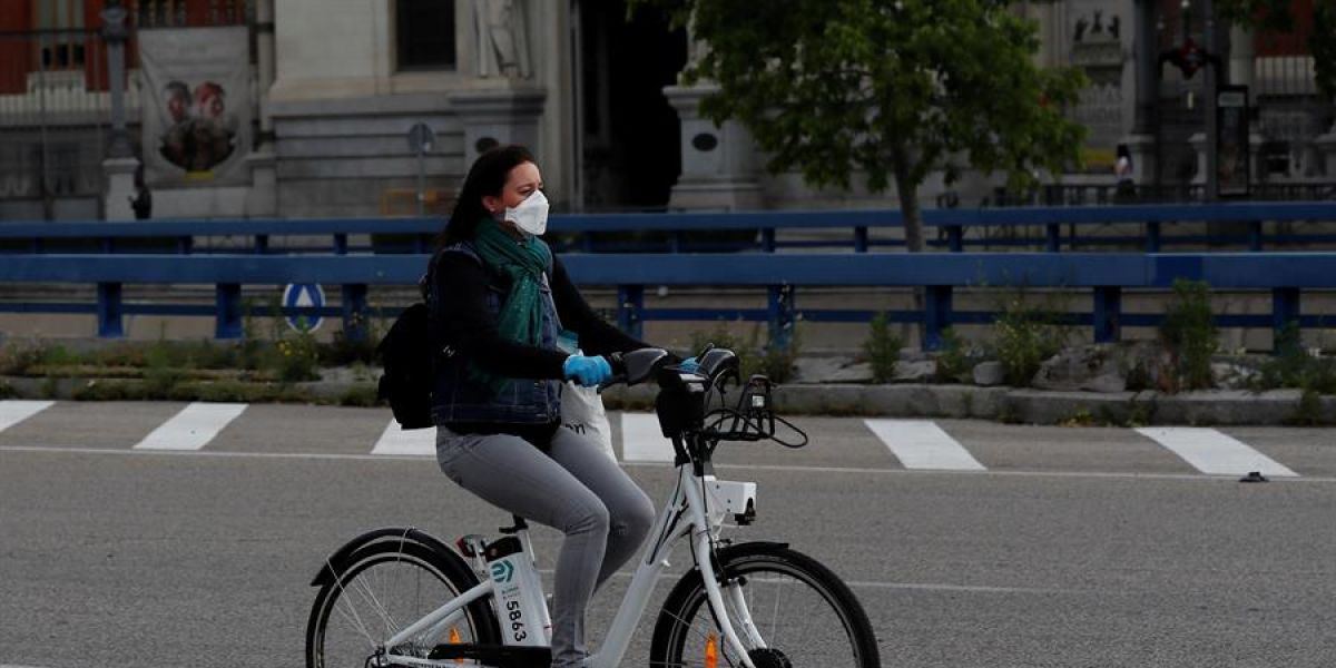 Una mujer con mascarilla y guantes usa una bici de biciMad en Madrid