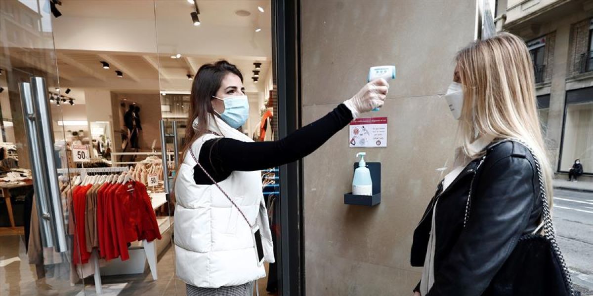 La encargada de una tienda de ropa toma la temperatura a una trabajadora