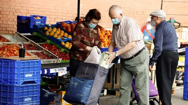 Varias personas hacen sus compras en un mercadillo en Madrid