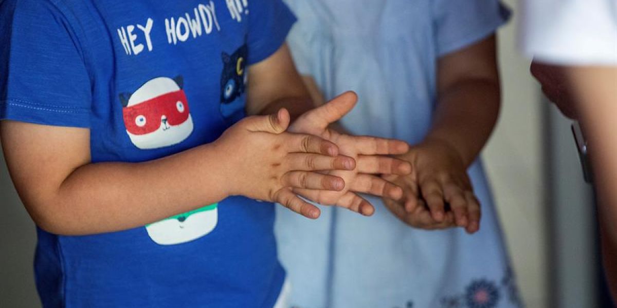 Dos niños de desinfectan las manos con gel hidroalcohólico