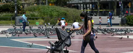 Una mujer con mascarilla empujando un carrito de bebé en Barcelona Una mujer con mascarilla empujando un carrito de bebé en Barcelona
